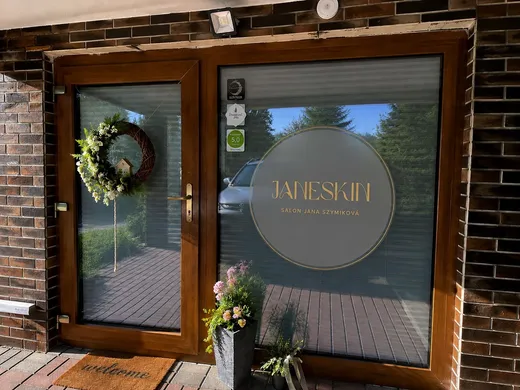 Kulatá samolepka s logem Janeskin na skleněných dveřích salonu